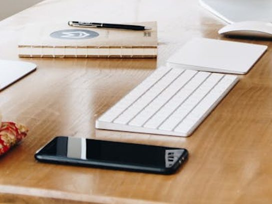 Un smartphone posé sur un bureau, à côté d'un clavier d'ordinateur